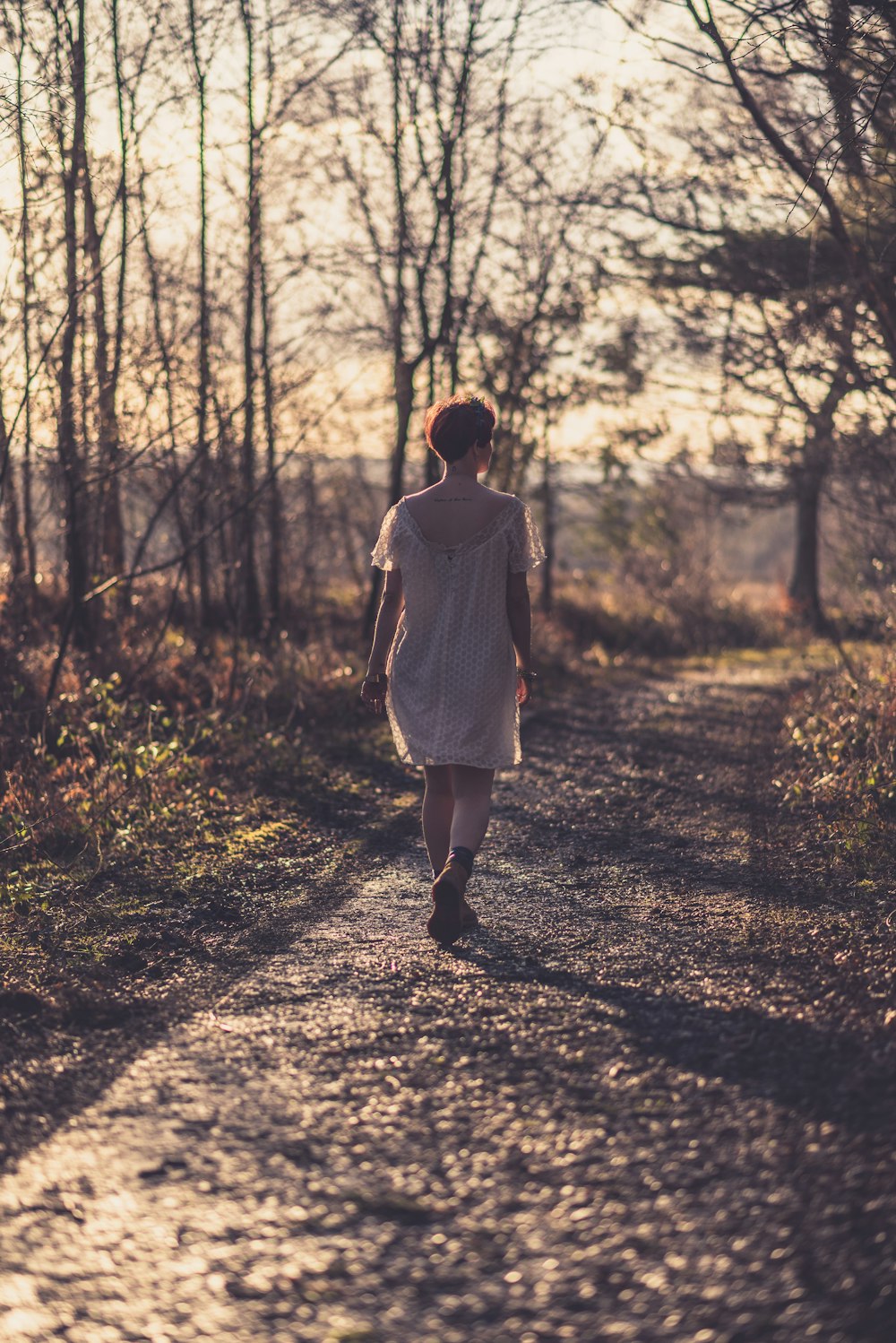 mujer caminando por el camino rural rodeada de árboles