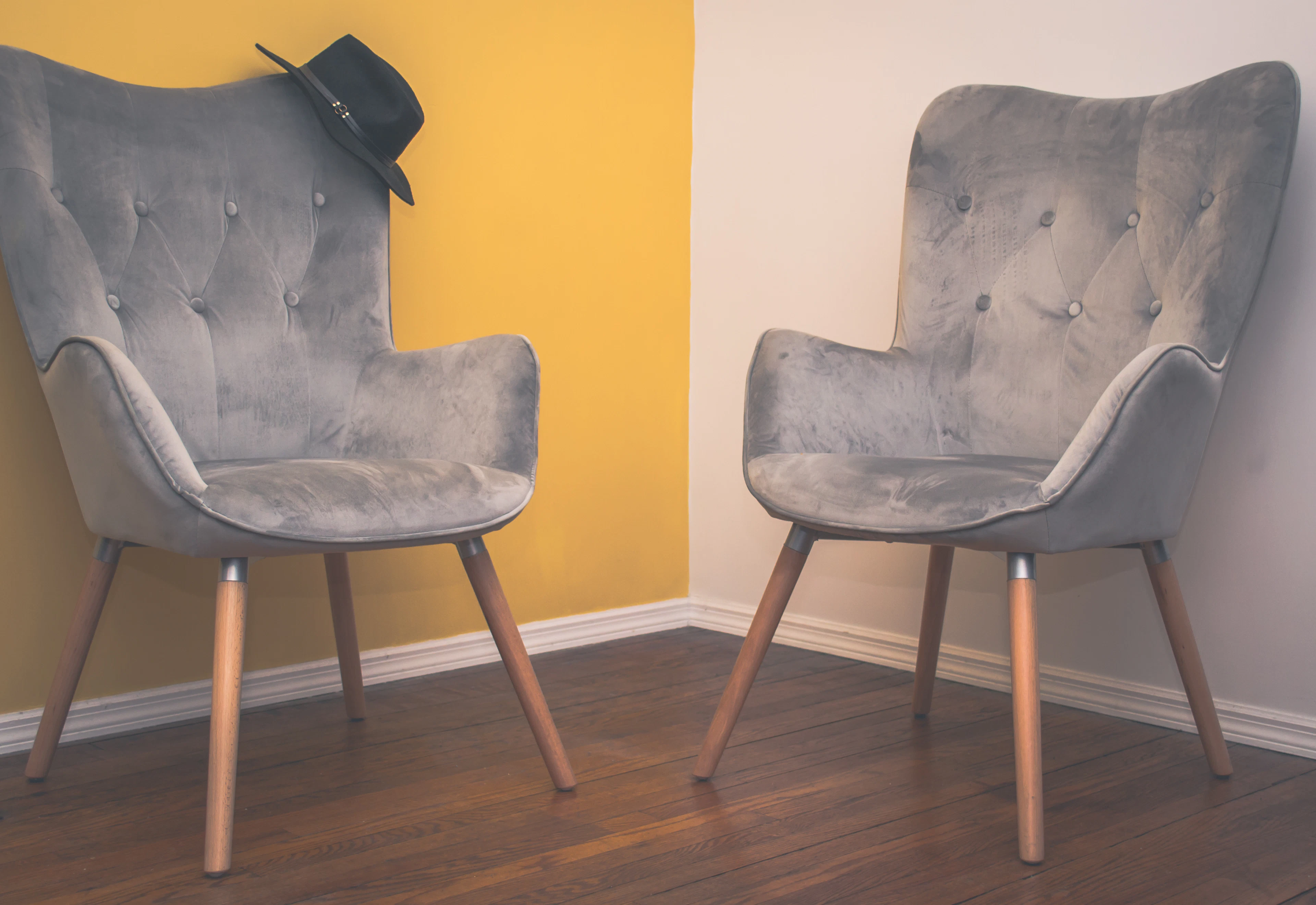 Two grey upholstered wingback chairs on wooden legs