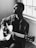grayscale photography of man playing acoustic guitar