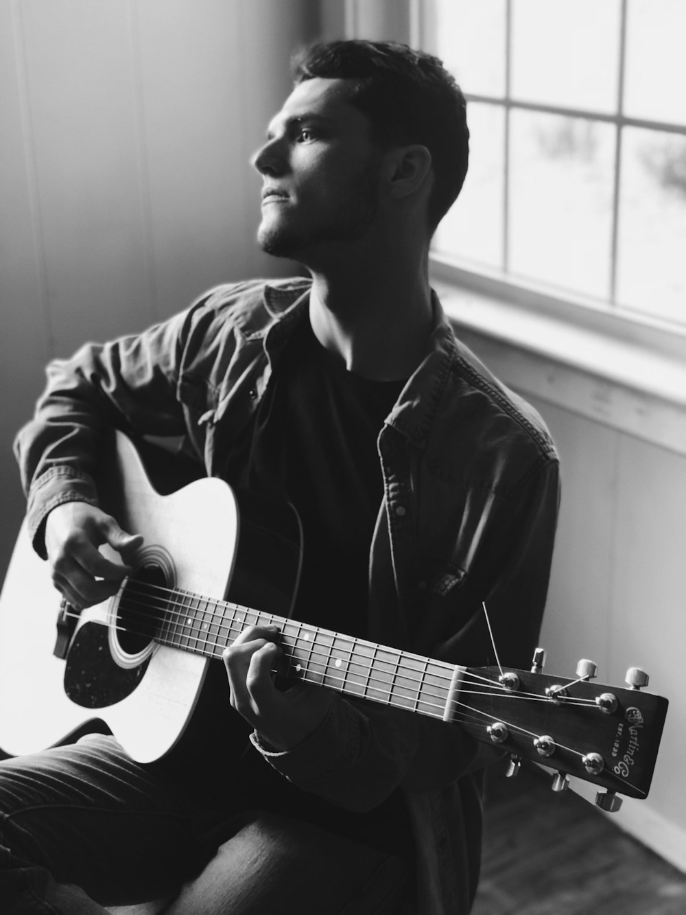 grayscale photography of man playing acoustic guitar