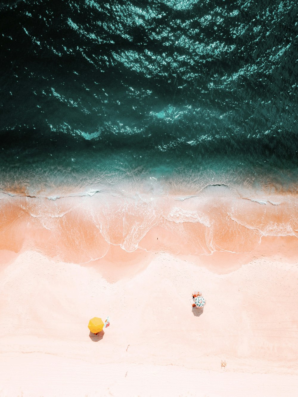bird's eye view of two yellow and green umbrellas on beach