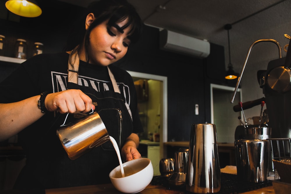 woman pouring a milk on bowl