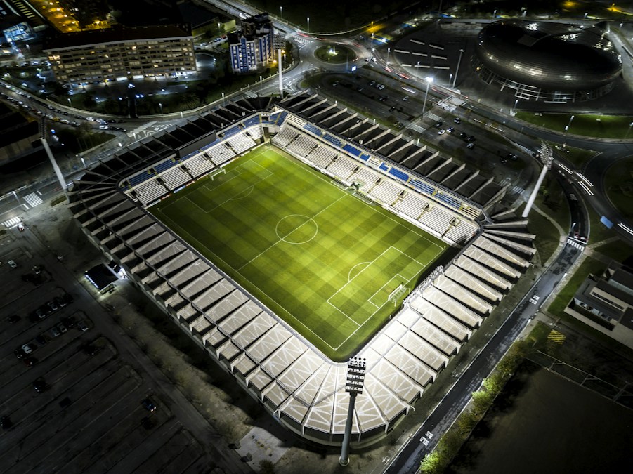 Vue aérienne d’un stade de football éclairé de nuit, tribunes vides autour de la pelouse
