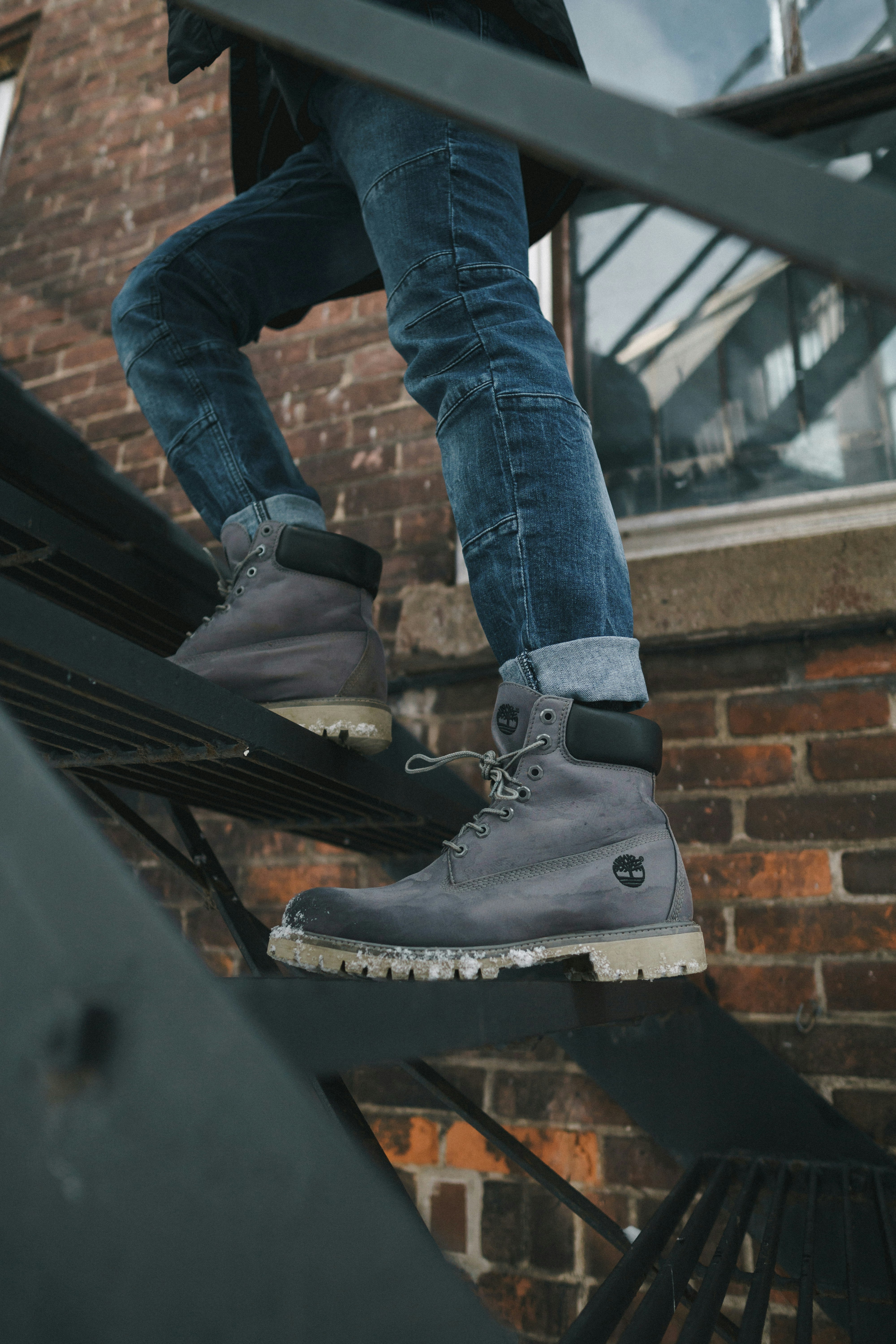 person wearing gray Timberland work boots climbing on black metal stairs