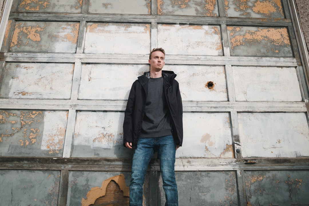 man leaning on white wooden wall