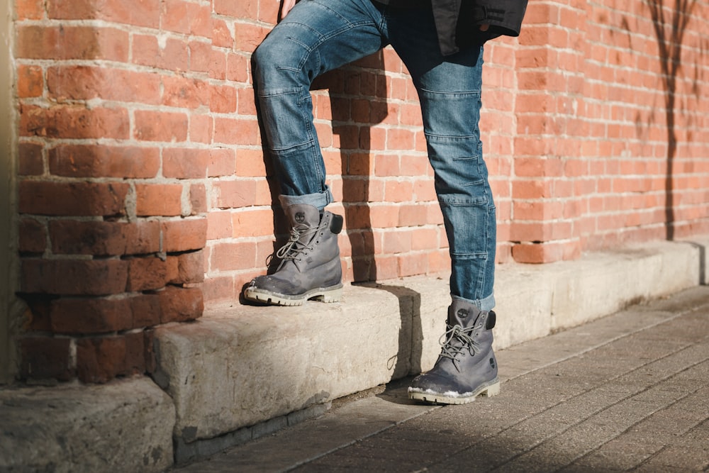 person standing beside brown brick wall