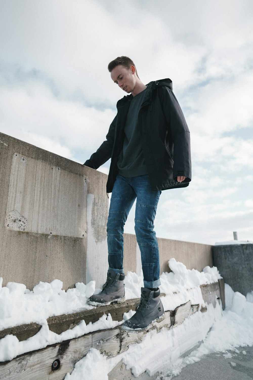 uomo in piedi accanto alla copertura del muro dalla neve