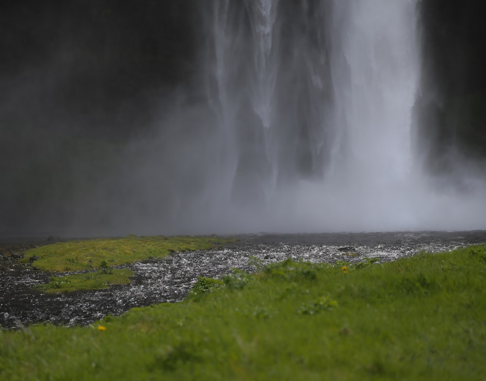 photo of waterfalls near green grass field