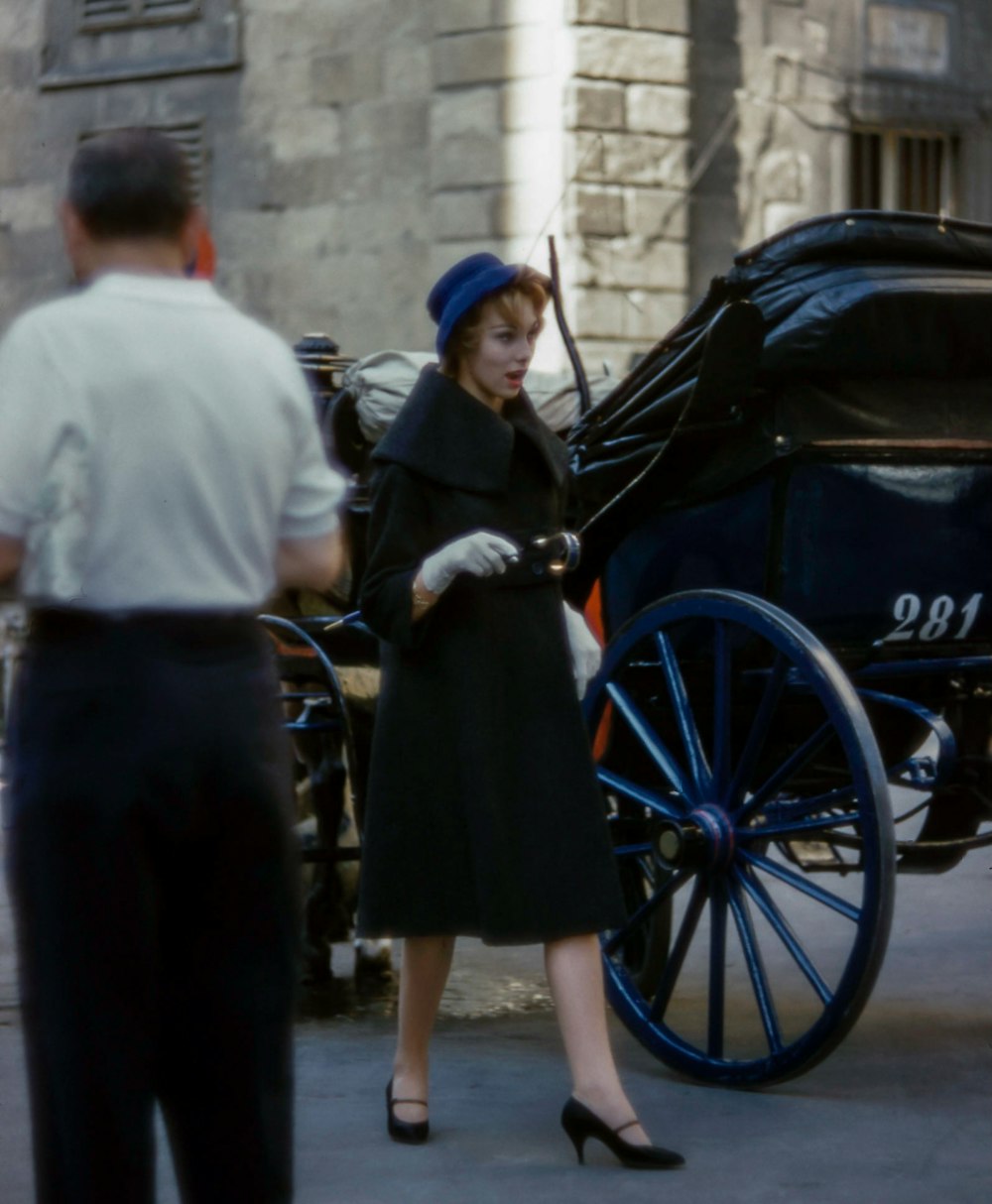 a woman standing next to a horse drawn carriage