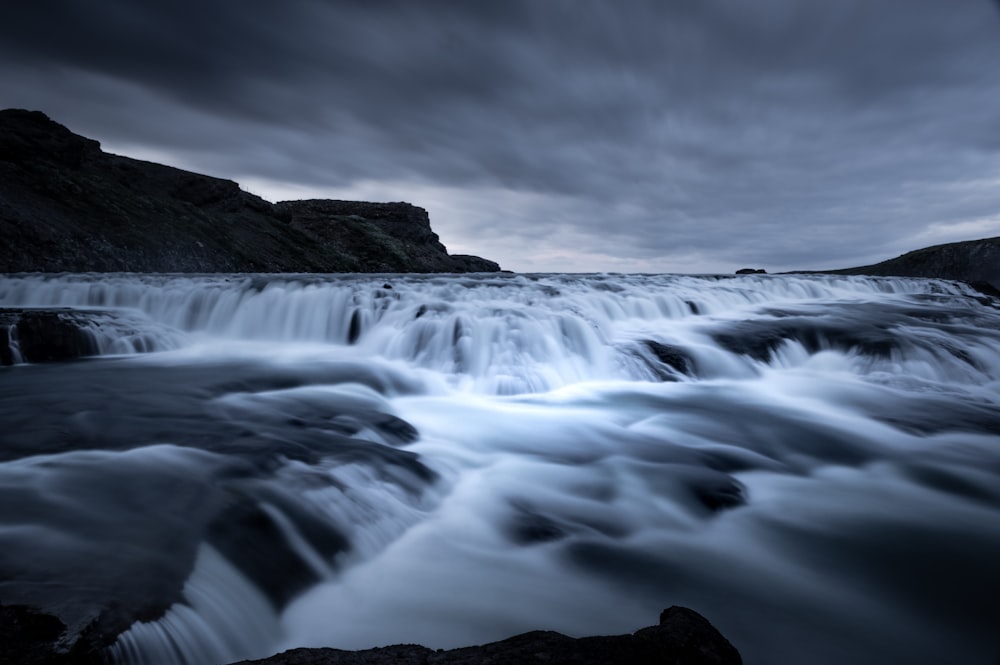 water flows near mountain under dark sky