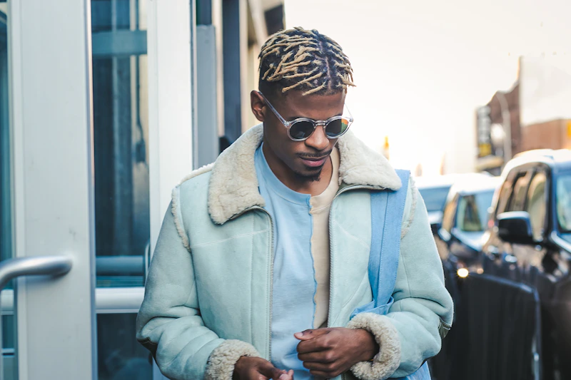 man wearing teal jacket and sunglasses confidently