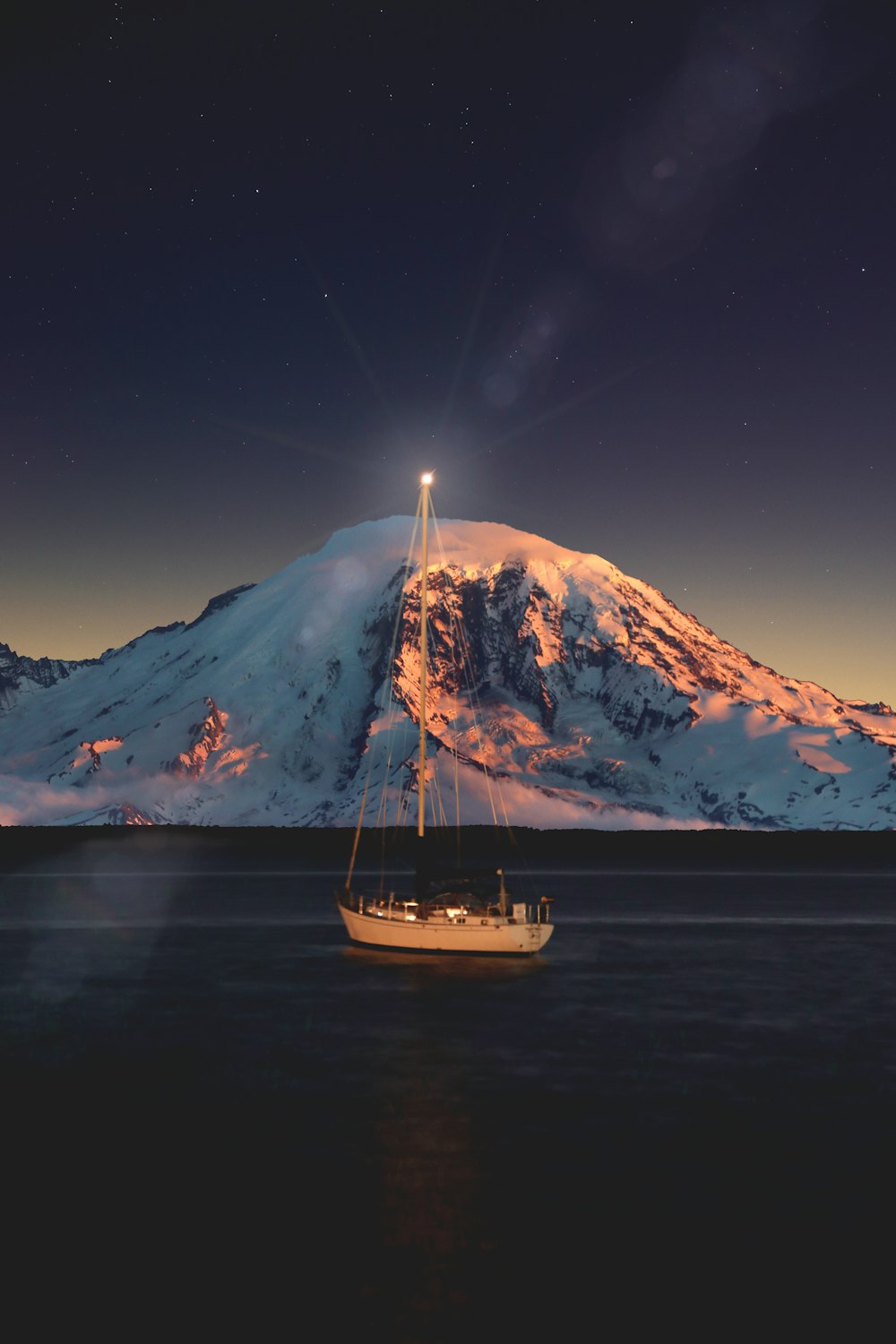 sailboat sailing near snowcapped mountains