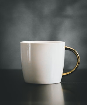 white and beige ceramic mug on black surface