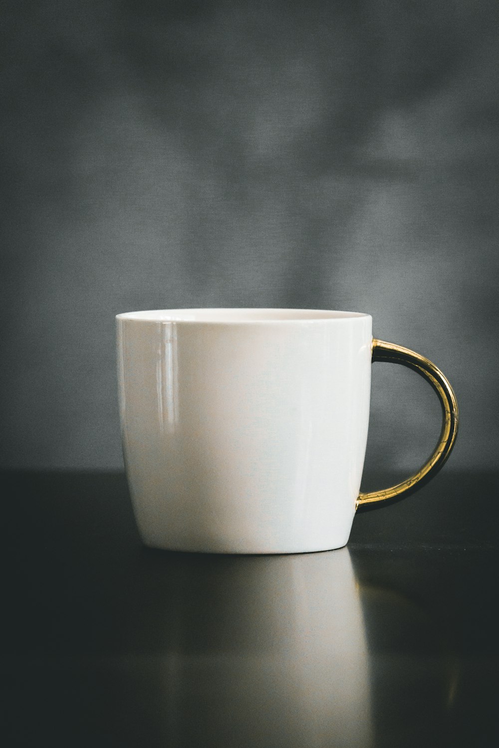 white and beige ceramic mug on black surface