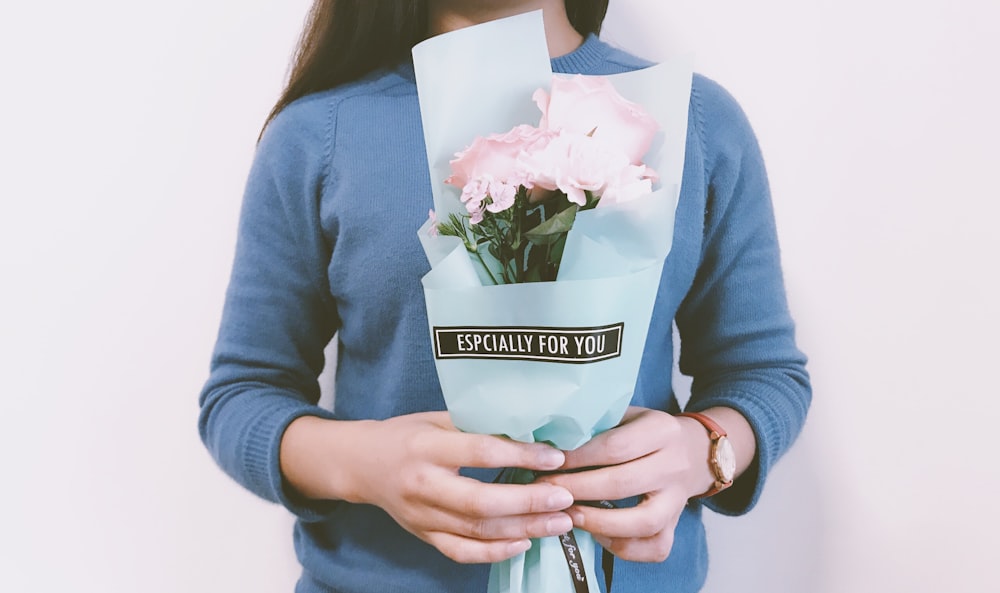 mujer sosteniendo ramo de flores rosas