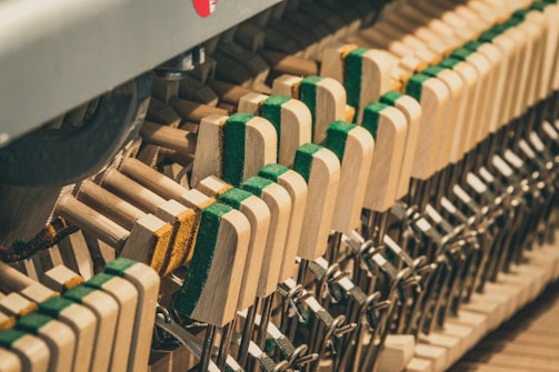 Technician repairing worn piano hammers with specialized tools.