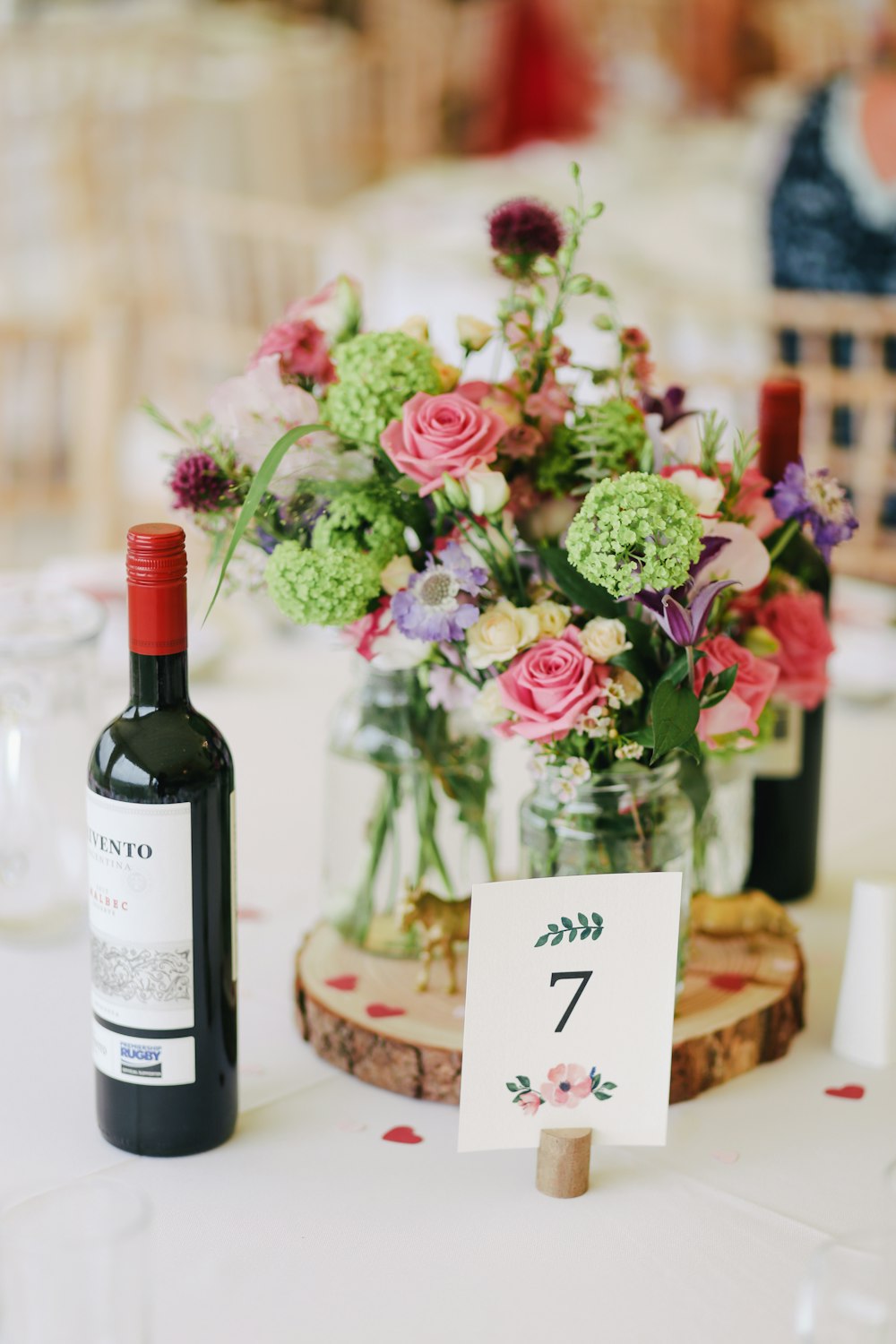 Arreglo floral con botella de vino en la mesa