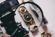person using magnifying glass to see gold and white device gear
