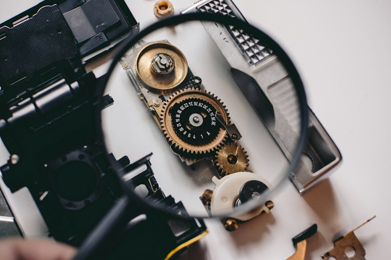 A magnifying glass held over a small brass gear, illustrating the fine tolerances involved in hand-cut gearing