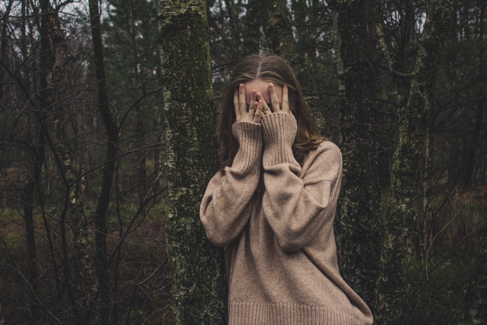 femme portant un chandail marron debout sur la forêt