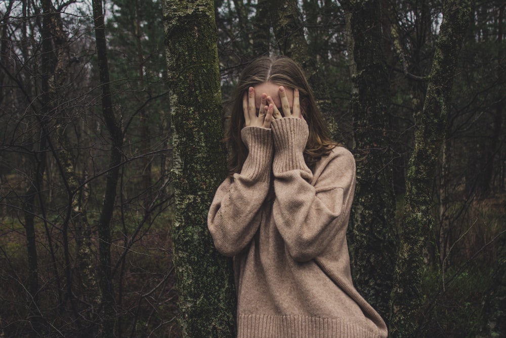 woman wearing brown sweater standing on forest