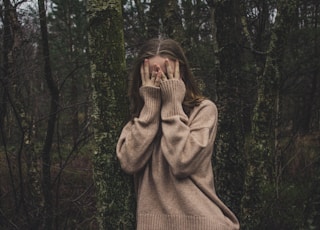 woman wearing brown sweater standing on forest