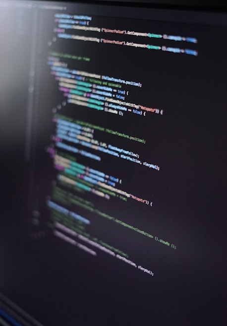 A close-up of a computer screen displaying lines of code in an integrated development environment. The code is colorful, with syntax highlighting for various programming elements such as keywords, strings, and functions. The text appears to be in a high-level programming language, possibly JavaScript or C#.