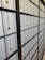 A row of metal post office boxes with numbers and keyholes, arranged in a grid pattern, creating a repetitive and organized visual effect. The boxes are metallic silver with black numerals and are framed by a black structure.