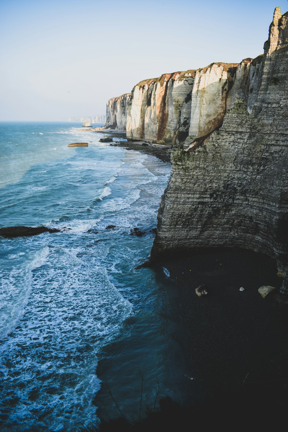 gray cliff beside body of water