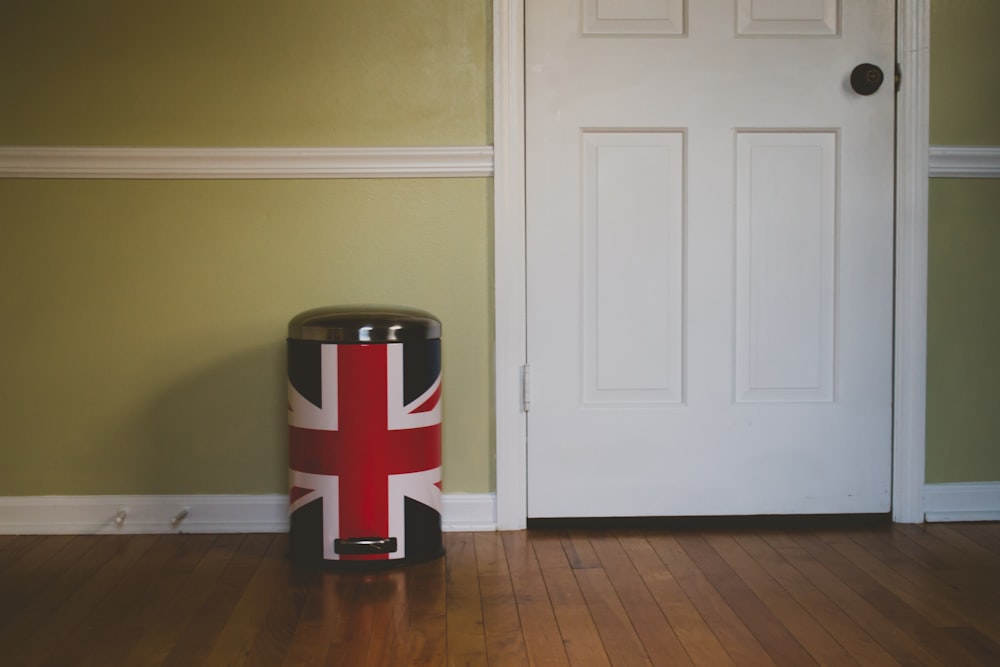 black and red UK flag pedal trash bin near white wooden door