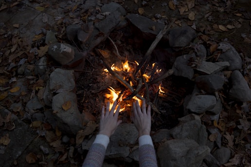 photography of person warming his/her hands at bonfire