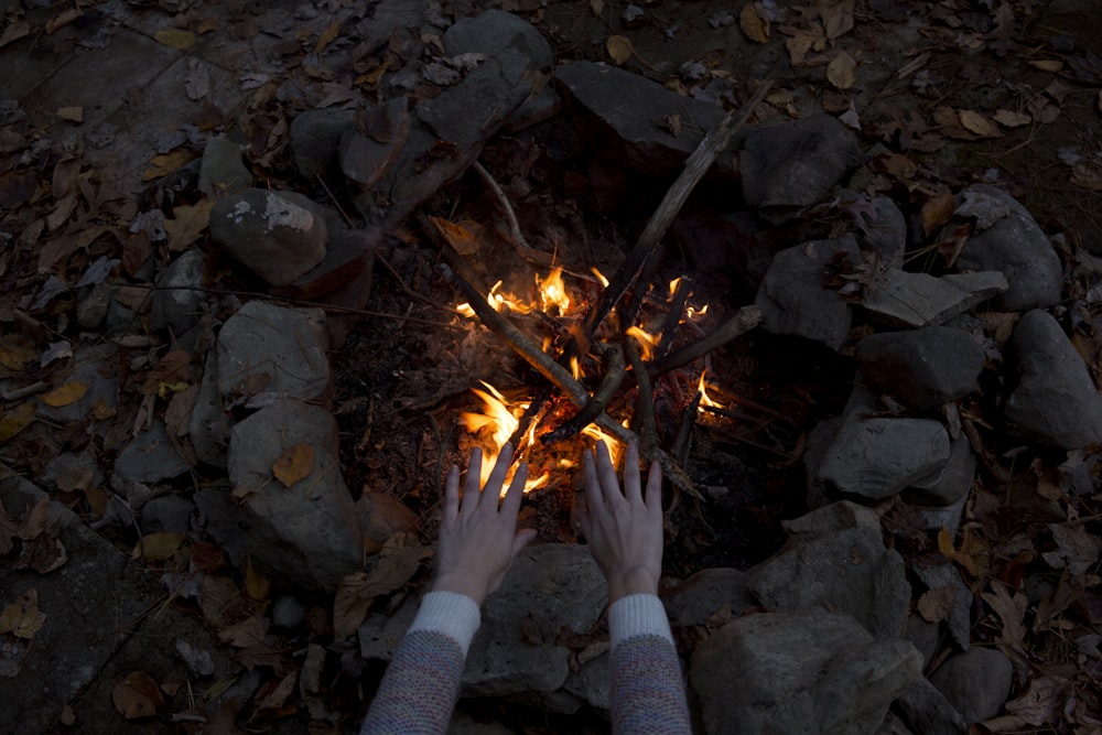 photography of person warming his/her hands at bonfire