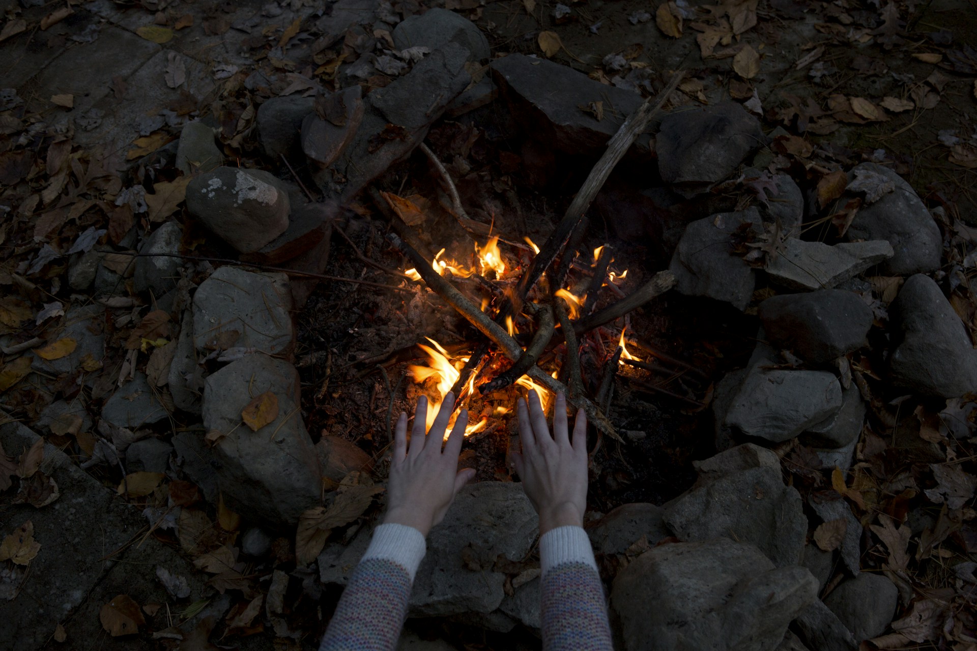 photography of person warming his/her hands at bonfire