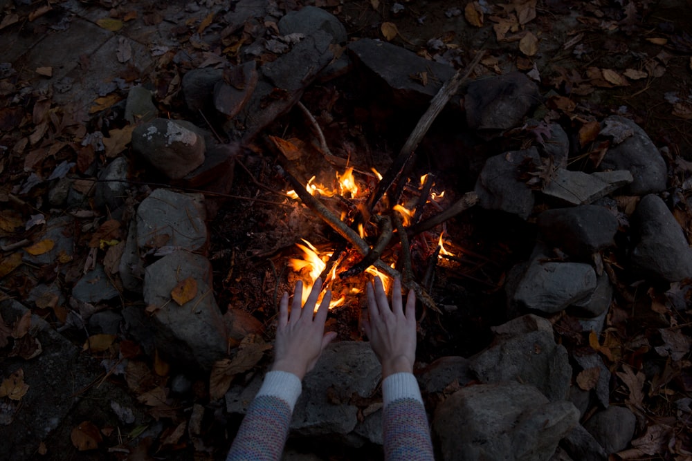 photography of person warming his/her hands at bonfire