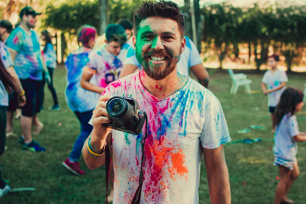 man holding DSLR camera with paint on face