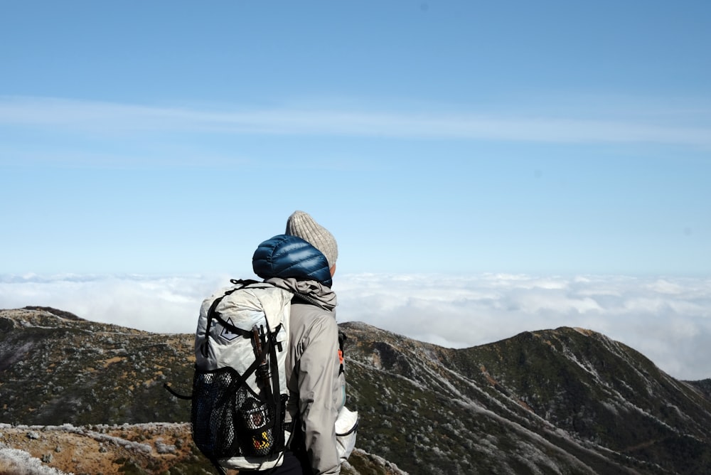 person standing on brown mountain under blue and white sky