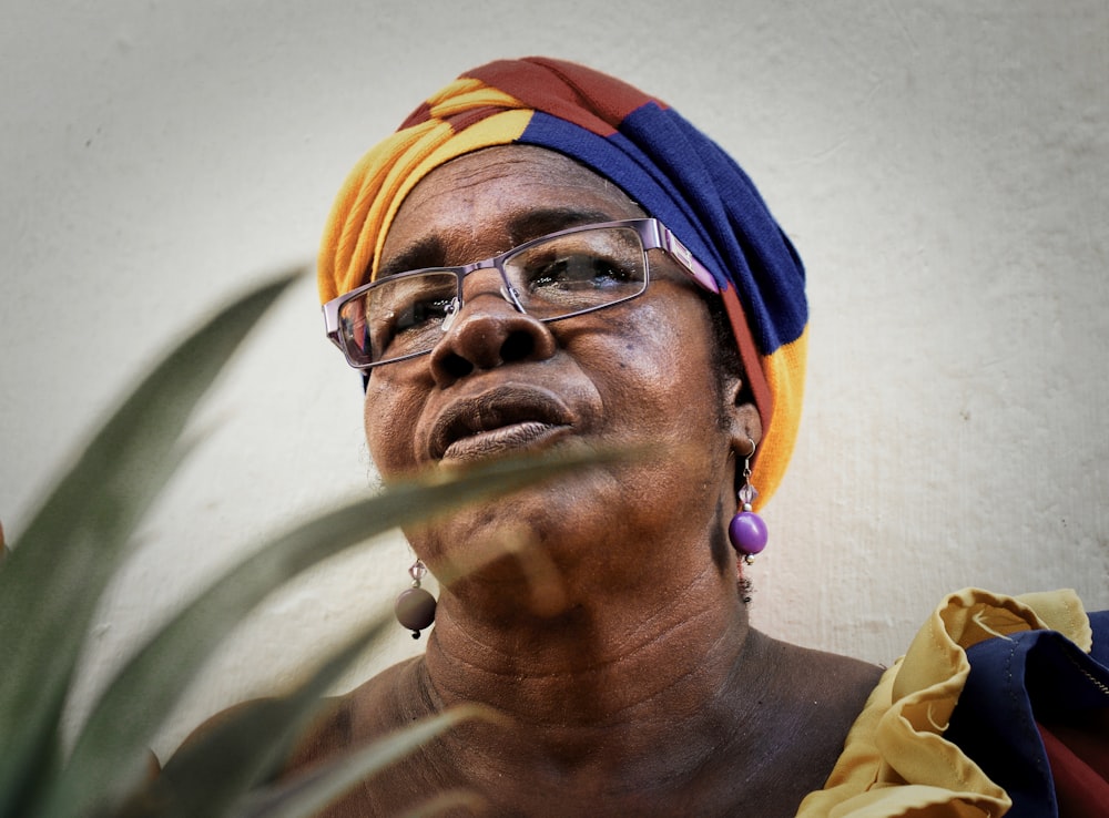 woman wearing yellow, blue, and brown headdress and eyeglasses