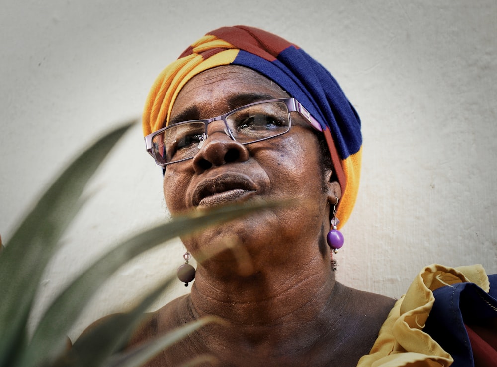 Femme portant une coiffe et des lunettes jaunes, bleues et brunes