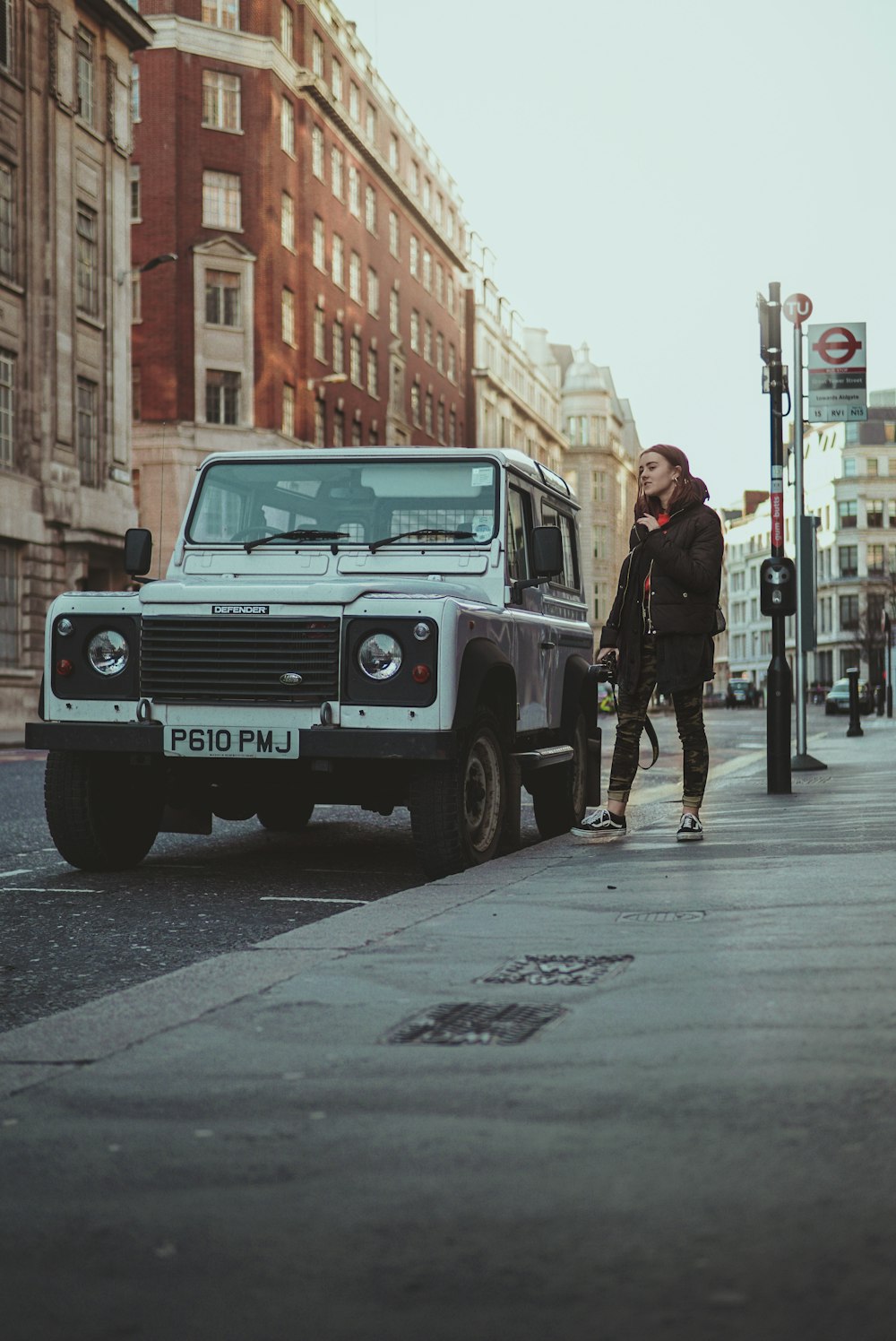 woman standing beside white SUV on street at daytime