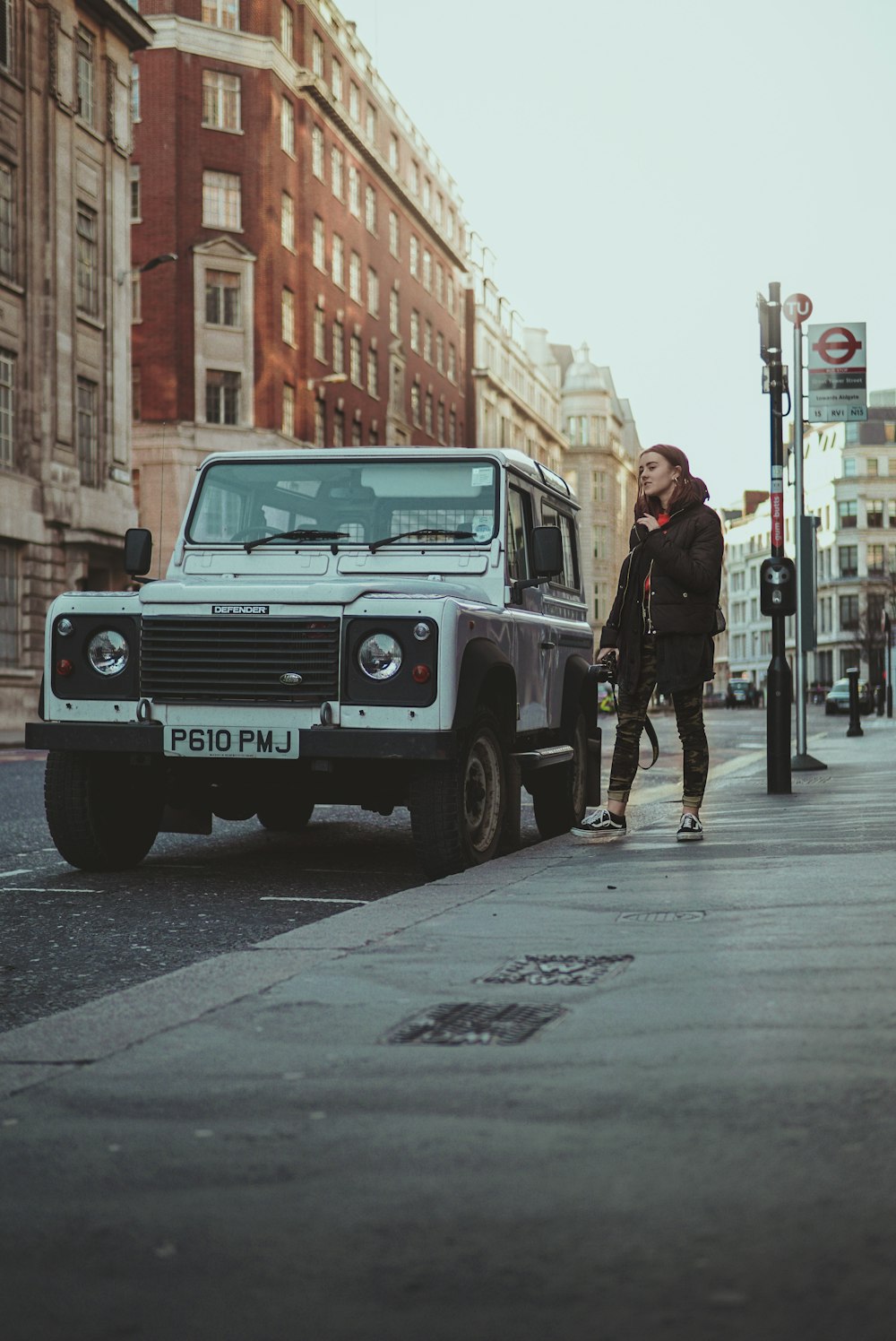 mujer de pie junto a SUV blanco en la calle durante el día