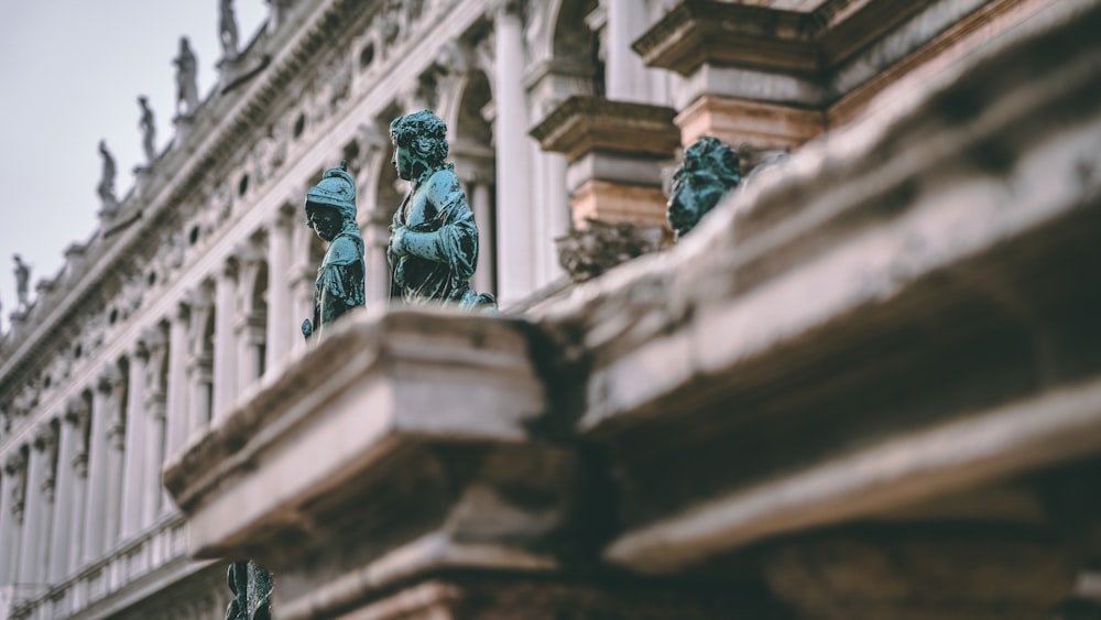 human statues near white building