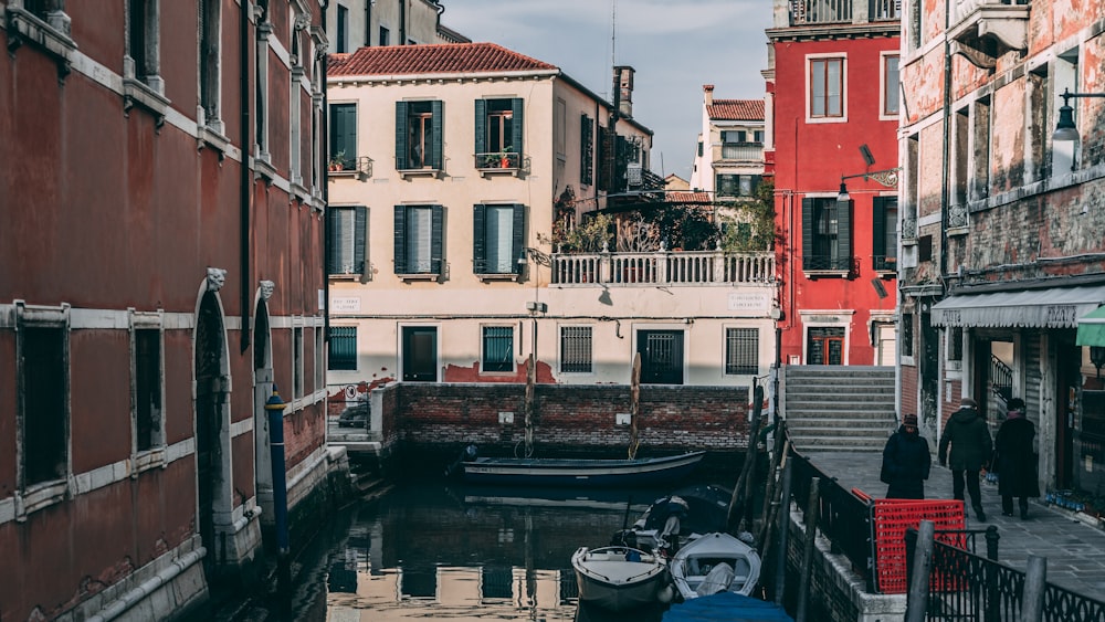 people walking beside body of water in city