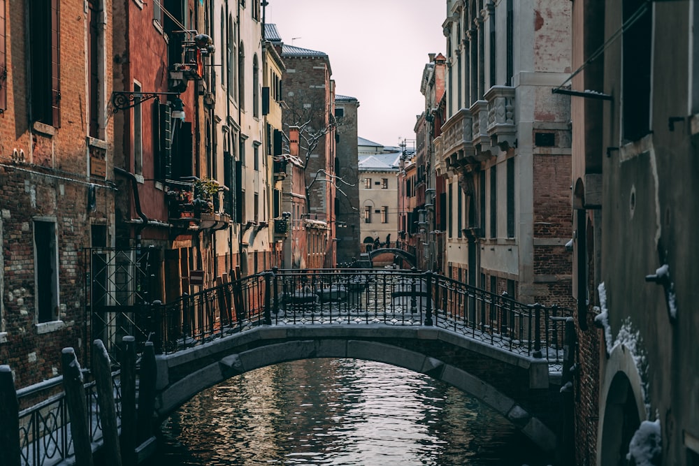 ヴェネツィア運河に架かる灰色と黒の橋、日中は茶色の家々の近く