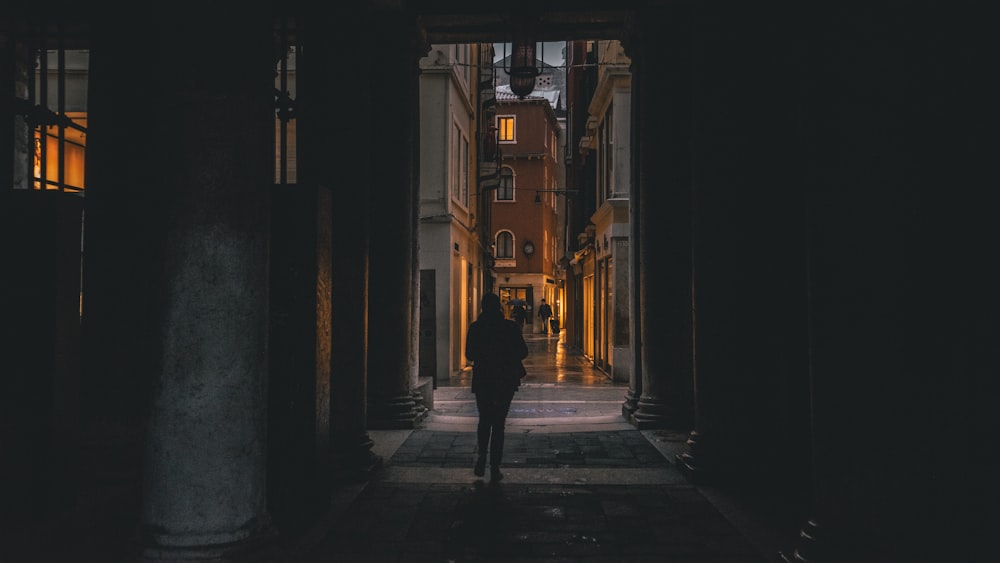 photography of person walking inside archway