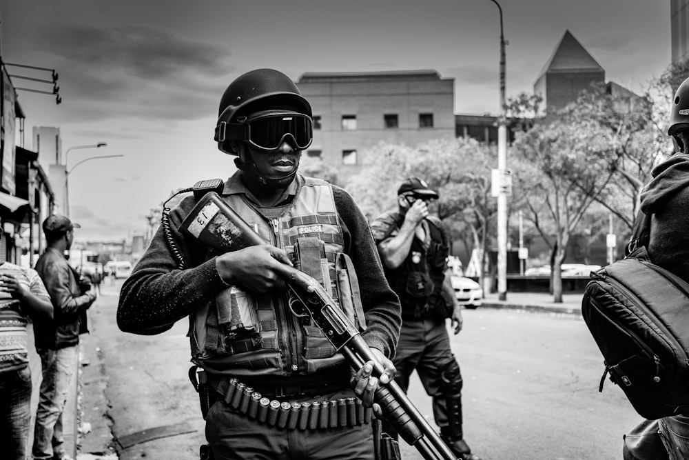 Foto en escala de grises de un soldado que lleva un rifle de bombeo