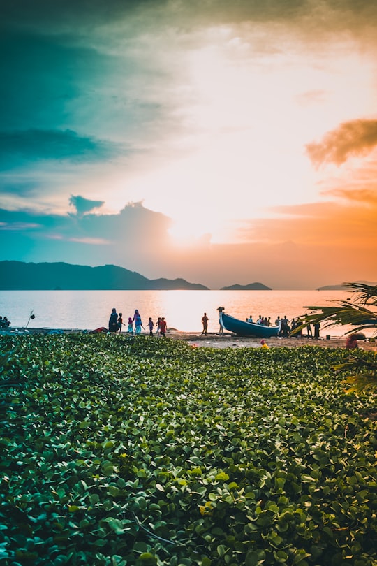 people in the beach near blue canoe at sunset in Ulee Lheue Indonesia