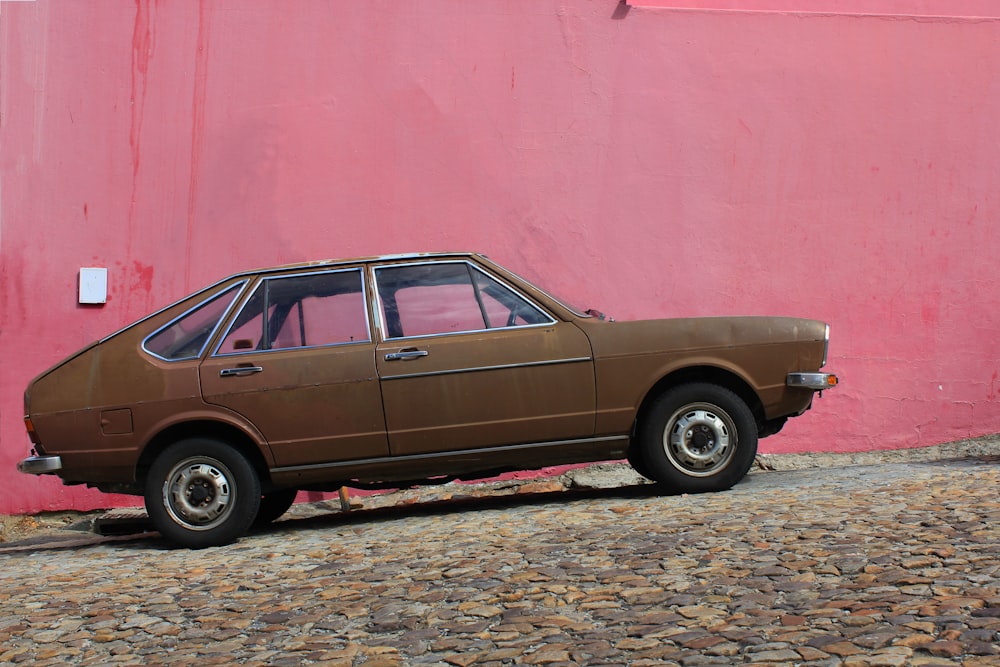 brown 5-door hatchback park beside red wall