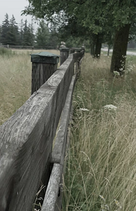 A weathered wooden fence bordering a sprawling Texas ranch at sunset.