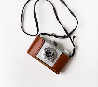 brown and gray SLR camera on white surface