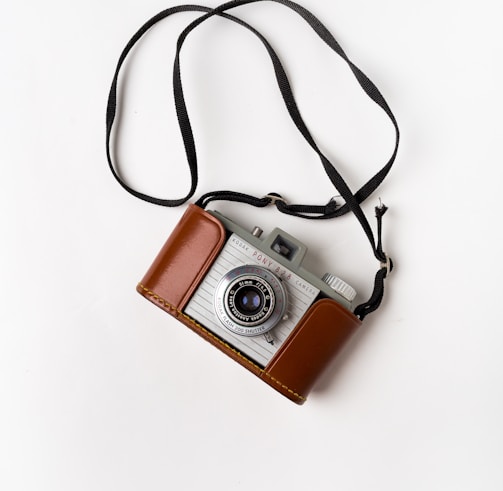 brown and gray SLR camera on white surface